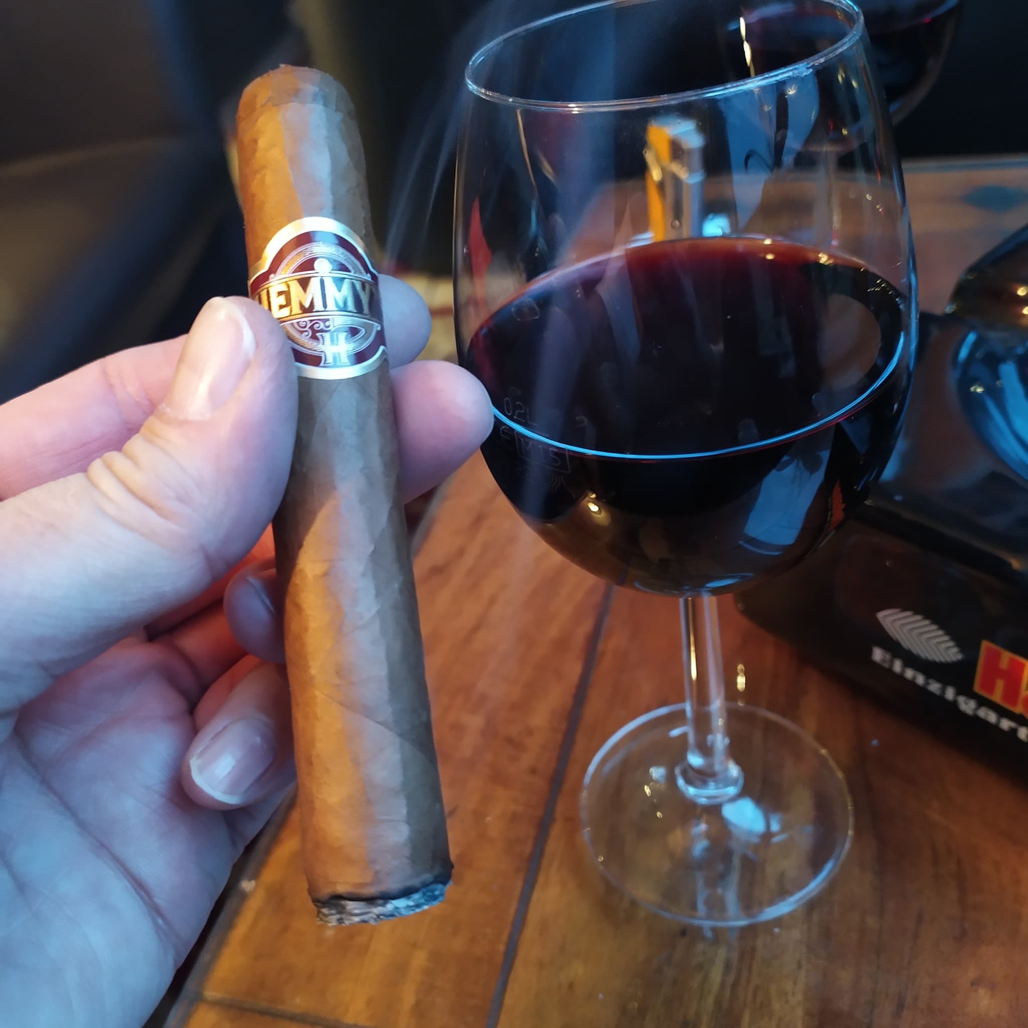 Zigarre und Rotwein in Hand